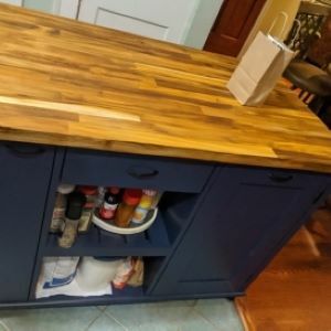 blue kitchen island with wood top with shelf filled with spices