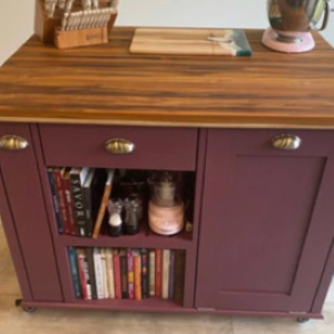 brownish red kitchen island with wood top with books on shelf
