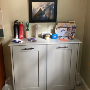 gray trash bin cabinet with stuff on top