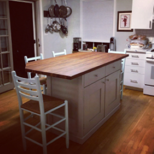 white kitchen island with wood top surrounded by chairs