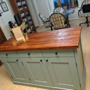 blue-gray kitchen island with wood top and bag and cutting board