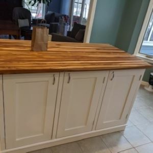 white kitchen island with wood top and bag