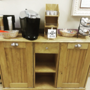 tan cabinet with shelf in middle with coffee items